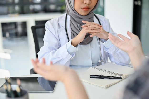 Médica muçulmana profissional conversando com seu paciente fazendo um exame de saúde sério