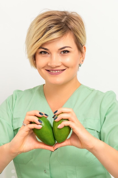 Médica nutricionista feminina vestindo roupa de trabalho verde segurando abacate orgânico verde Conceito de estilo de vida saudável