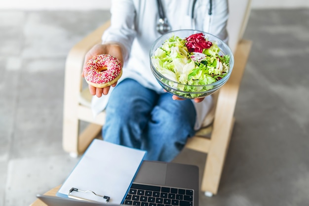 Médica nutricionista segurando comida saudável e junk food nas mãos