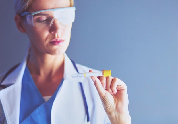 Médica o investigadora científica o doctora que mira un tubo de ensayo de solución clara en un laboratorio o laboratorio