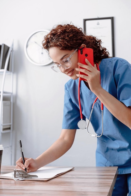 Médica recebendo uma chamada fazendo anotações conceito de atendimento ao paciente