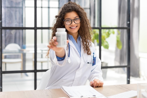 Médica segurando tablets trabalhando na mesa de escritório e sorrindo para a câmera