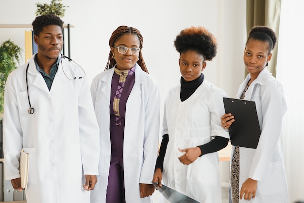 Médica segurando um estetoscópio com sua equipe atrás