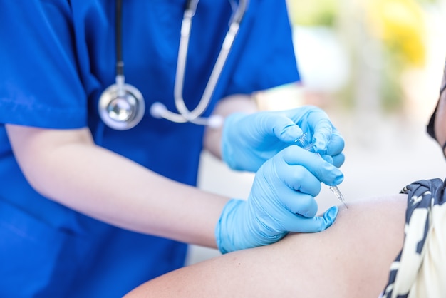Médica segurando uma seringa faz a injeção no paciente em vacinas médicas