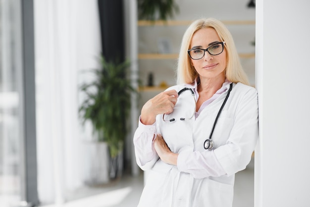 Médica sênior caucasiana madura bem-sucedida em jaleco branco no hospital