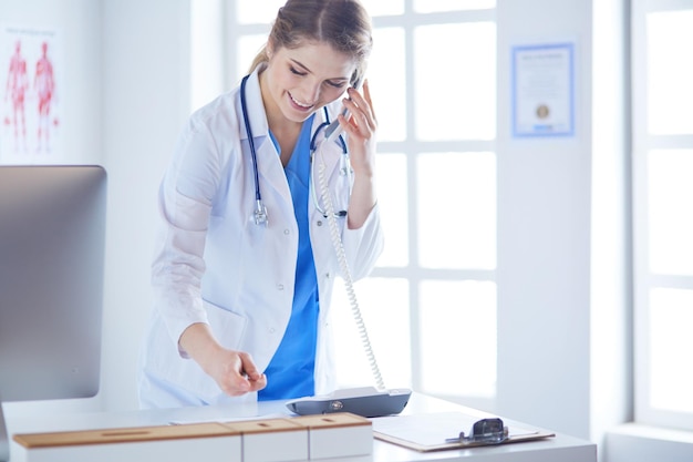 Médica séria ao telefone em seu escritório