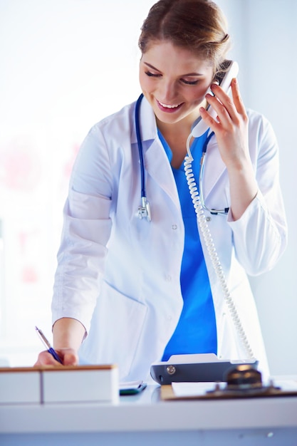 Médica séria ao telefone em seu escritório