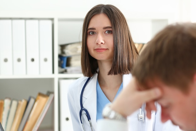 Médica simpática mantém o ombro do paciente no escritório durante a recepção.