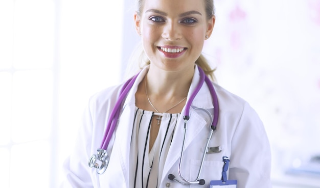 Médica sorridente com um estetoscópio médico em uniforme de pé