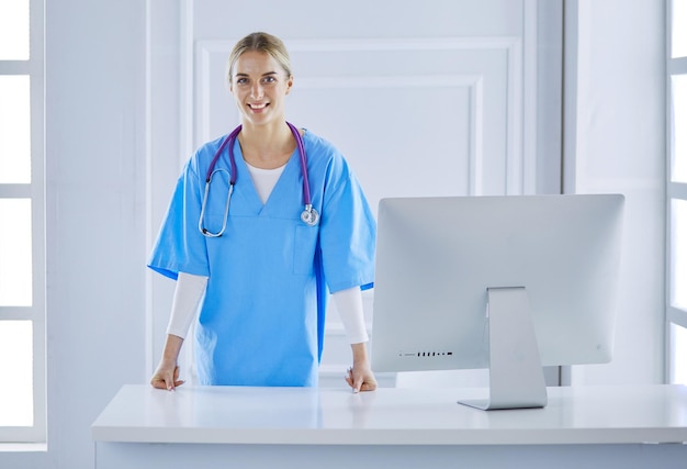 Médica sorridente com uma pasta em pé de uniforme