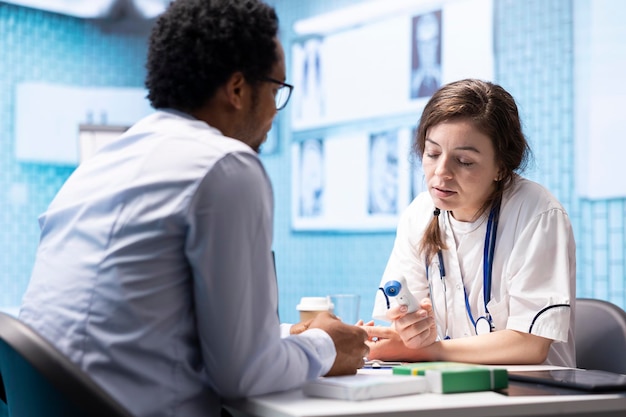 Médica tomando a temperatura de um paciente no consultório médico