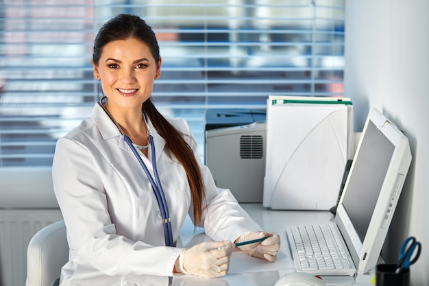 Médica usando computador pc enquanto está sentado no local de trabalho, ela é um local de trabalho do médico. conceito de saúde, seguro e medicina