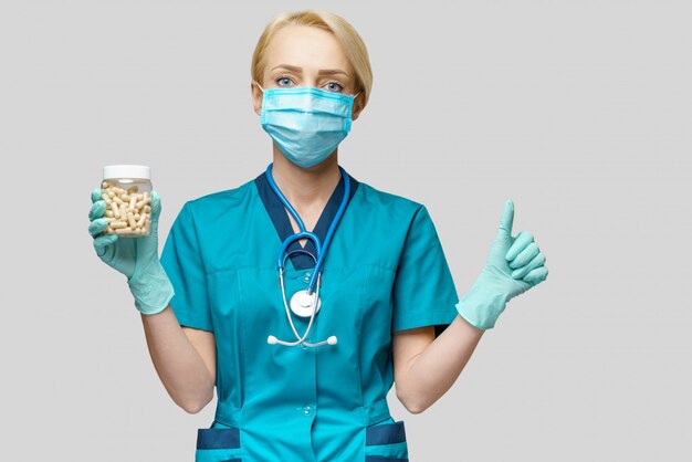 Médica, usando máscara protetora e luvas de látex segurando comprimidos