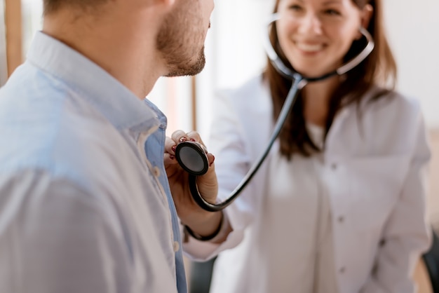 Médica, verificando o batimento cardíaco do paciente.