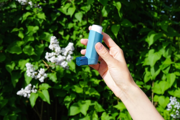 Foto medicamento farmacéutico para el alivio de un ataque de asma la mano de una mujer joven sostiene un inhalador azul para el asma concepto médico y de salud