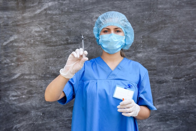 Medicamento. Mujer médico en uniforme protector con máscara en la cara con jeringa