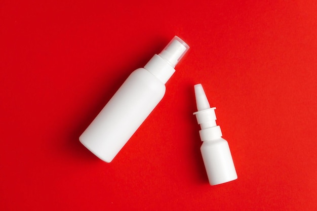 Medicamentos para tratamento de nariz e garganta Garrafas de spray nasal e garganta em fundo vermelho Mockup
