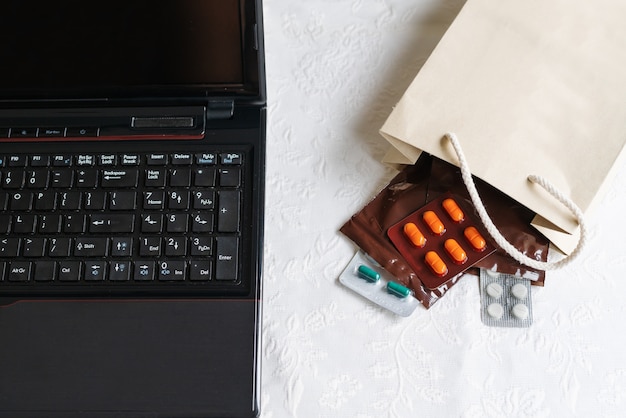 Medicamentos y pastillas al lado de la computadora portátil, teclado del cuaderno. Estrés en el trabajo