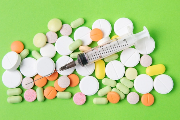 Medicamentos píldoras, medicamentos y antibióticos sobre un fondo verde. Medicina y cuidado de la salud.