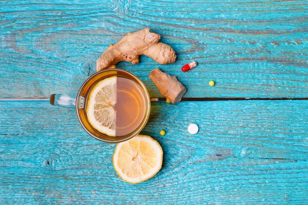 Medicamentos para el resfriado, té, limón y jengibre en azul madera