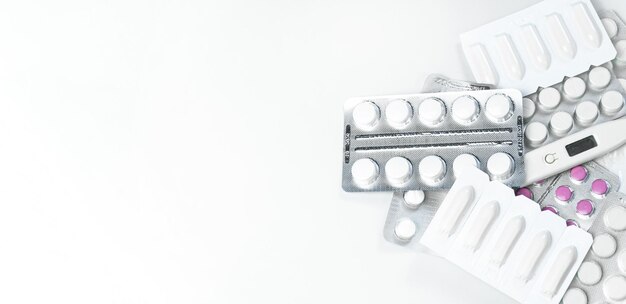 Foto medicamentos sobre un fondo blanco píldoras y un termómetro se mezclan en un fondo blanco bandera