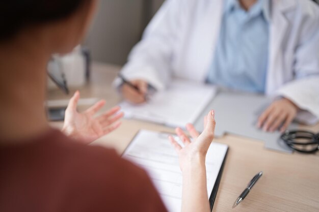 Médicas dentistas asiáticas sosteniendo un modelo de mandíbulas humanas con dientes explicando sobre tratamientos dentales orales a una paciente femenina mientras examinan los dientes y discuten sobre la salud dental en la clínica dental