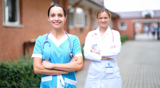 Médicas en uniforme de pie cerca de la clínica