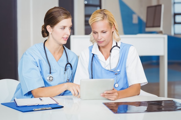 Médicas usando tablet digital enquanto está sentado na mesa