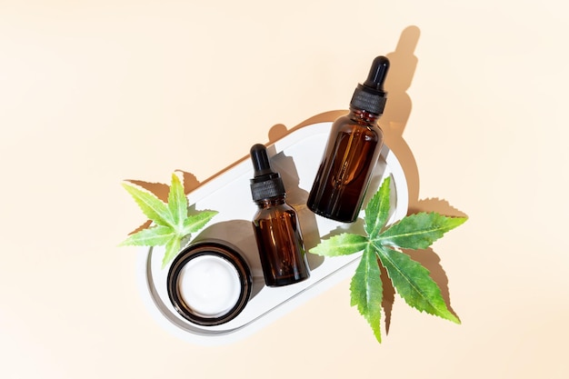 Medicina alternativa, cosmética natural, aceite de cbd, crema facial en frasco abierto y hojas de cannabis, cosmética, vista superior, espacio de copia, diseño de maqueta.