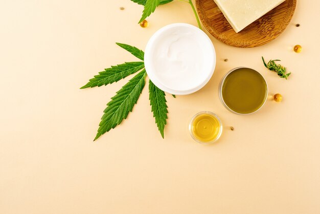 Medicina alternativa, cosméticos naturais. óleo cbd e cannabis deixa cosméticos vista de cima em fundo laranja, plano plano