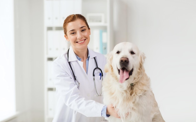 medicina, animal de estimação, animais, cuidados de saúde e conceito de pessoas - feliz veterinário ou médico com cachorro golden retriever na clínica veterinária