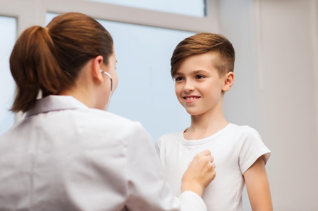 medicina, atención de la salud y concepto de personas - doctora o enfermera con estetoscopio escuchando el pecho de un niño feliz en el hospital