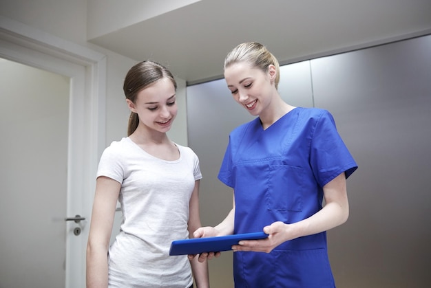 medicina, atención de la salud, tecnología y concepto de personas: doctora o enfermera sonriente con computadora de tablet pc y reunión de niñas en el hospital