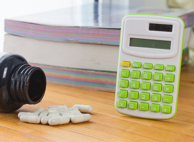 Medicina y calculadora en la mesa de madera,