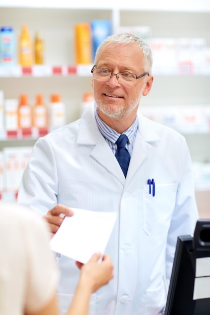 Foto medicina cuidado de la salud y el concepto de la gente boticario sénior tomando la receta del cliente en la farmacia