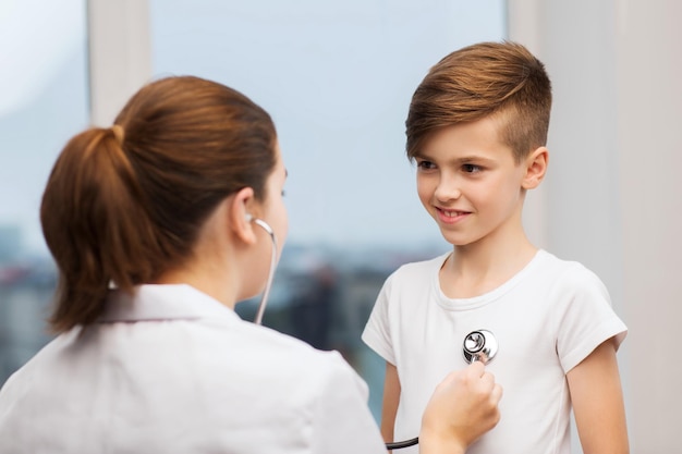 medicina, cuidados de saúde e conceito de pessoas - médica ou enfermeira com estetoscópio ouvindo o peito de uma criança feliz no hospital