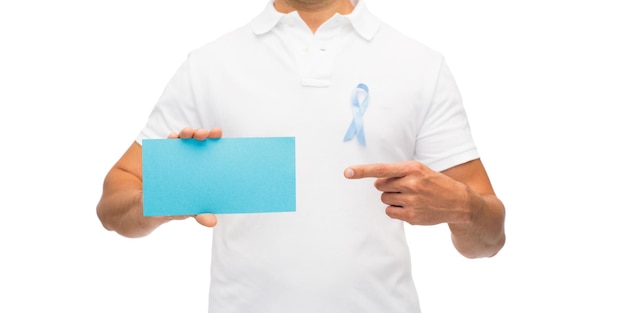 Foto medicina, cuidados de saúde, gesto e conceito de pessoas - close-up de homem latino de meia idade em t-shirt com fita de conscientização de câncer de próstata azul céu segurando o cartão de papel em branco