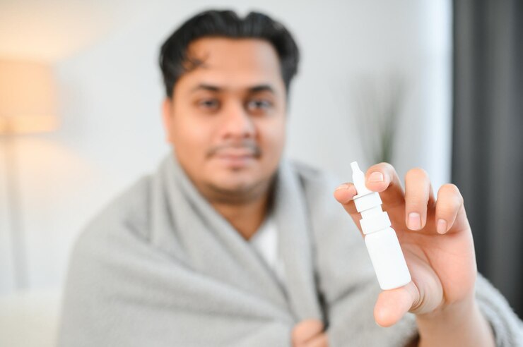 Foto medicina da rinite e conceito de cuidados de saúde homem indiano doente em cobertor usando spray nasal em casa