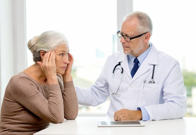 medicina, edad, atención de la salud y concepto de personas - anciana y médico con tablet pc reunión en el consultorio médico