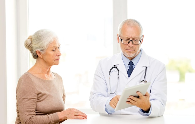 medicina, edad, atención de la salud y concepto de personas - anciana y médico con tablet pc reunión en el consultorio médico