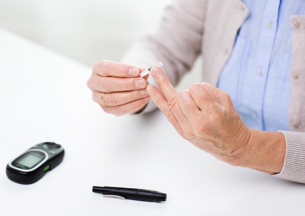 Medicina, edad, diabetes, atención médica y concepto de personas: cierre de una anciana con glucómetro que verifica el nivel de azúcar en la sangre en el hogar