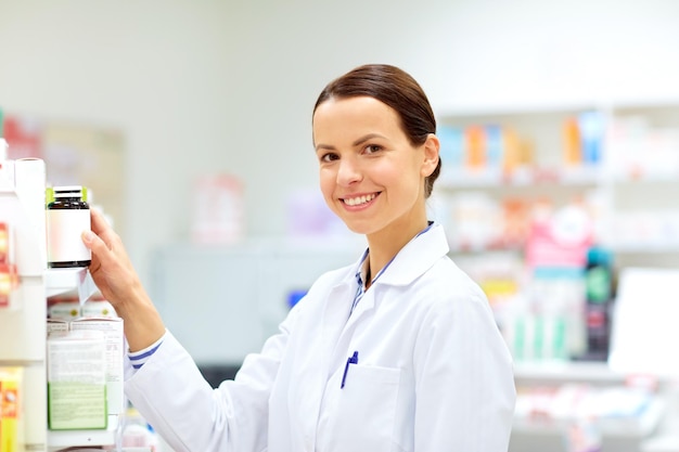 Foto medicina farmacéutica atención médica y conceptos de personas farmacéutica femenina feliz tomando medicamentos del estante en la farmacia