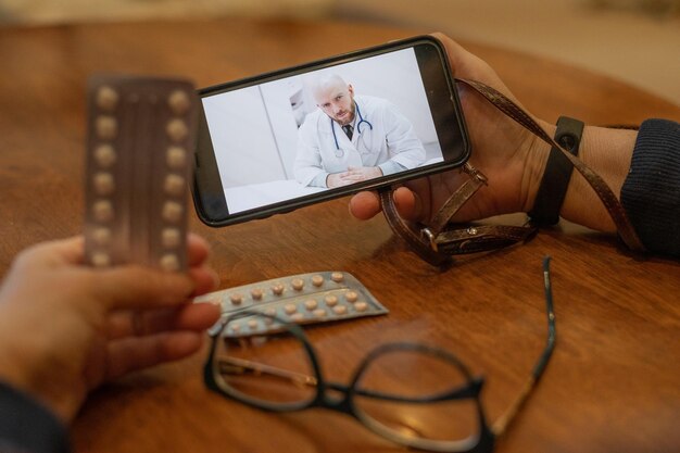 Medicina online Uma idosa com sintomas de coronavírus está conversando em um smartphone com um virologista Médico do sexo masculino ouve reclamações sobre a saúde de uma idosa no link do vídeo