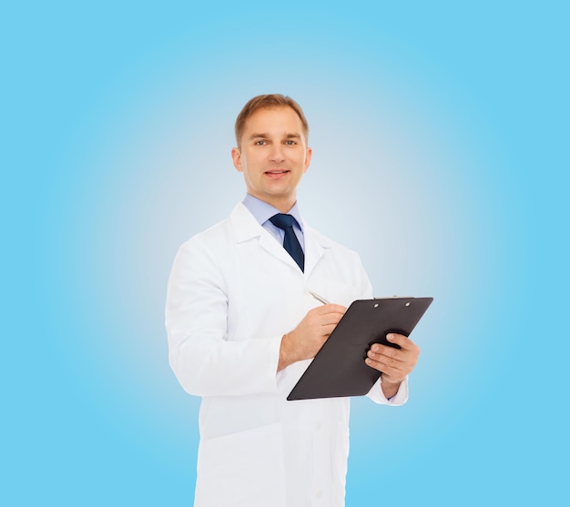 medicina, profesión y concepto de salud - médico sonriente con portapapeles escribiendo receta sobre fondo azul
