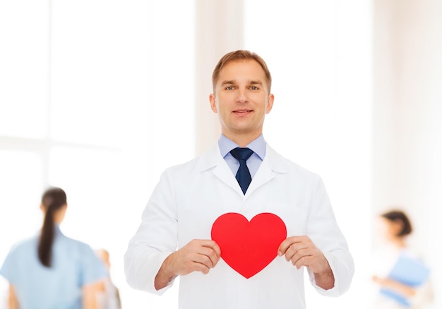 medicina, profissão, caridade e conceito de saúde - médico sorridente com coração vermelho sobre grupo de médicos