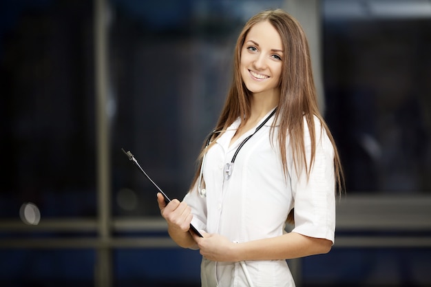 Medicina. retrato de un joven médico con una bata blanca de pie en el hospital. estudiante graduado. en el pasillo del hospital. médico de familia.