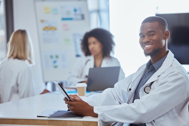 Medicina sanitaria y un médico en una tableta en una sala de juntas u oficina de un hospital después de una reunión o presentación Trabajador médico feliz con una sonrisa en línea en una mesa Médicos en un descanso para tomar café en el trabajo