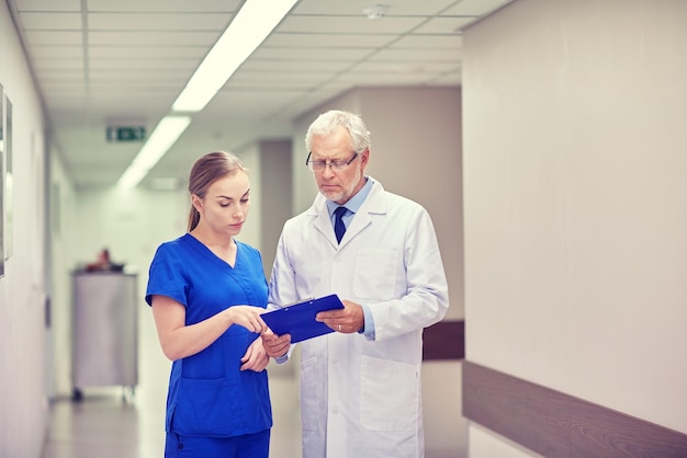 medicina, tecnología, atención de la salud y concepto de personas: médico senior y enfermera joven con computadora de tablet pc en la sala del hospital