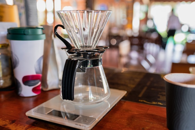 Medición de goteo de café con taza de vidrio en el mostrador