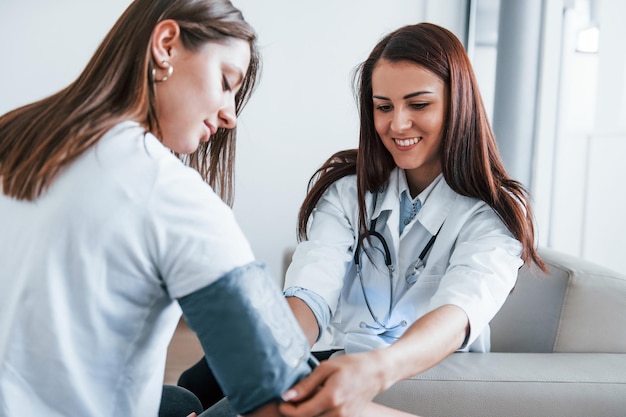 Medición de la presión arterial Una mujer joven tiene una visita a una doctora en una clínica moderna